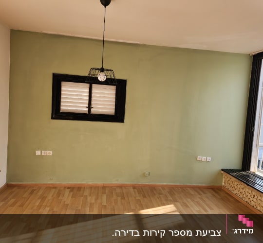 קיר צבוע בירוק עם חלון קטן ומנורה תלויה